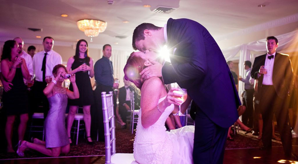 Bride a groom kiss on a dance floor at their wedding - by Anne Simone